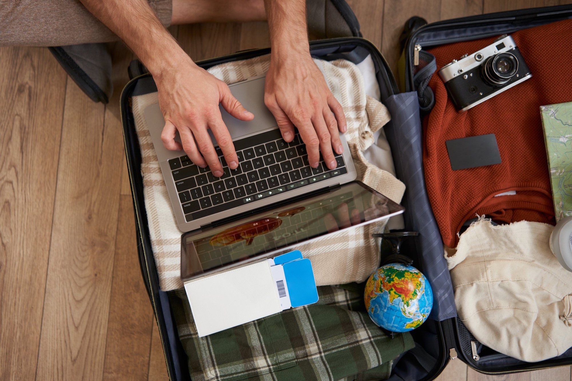 An open suitcase packed with a laptop, camera and travel essentials.