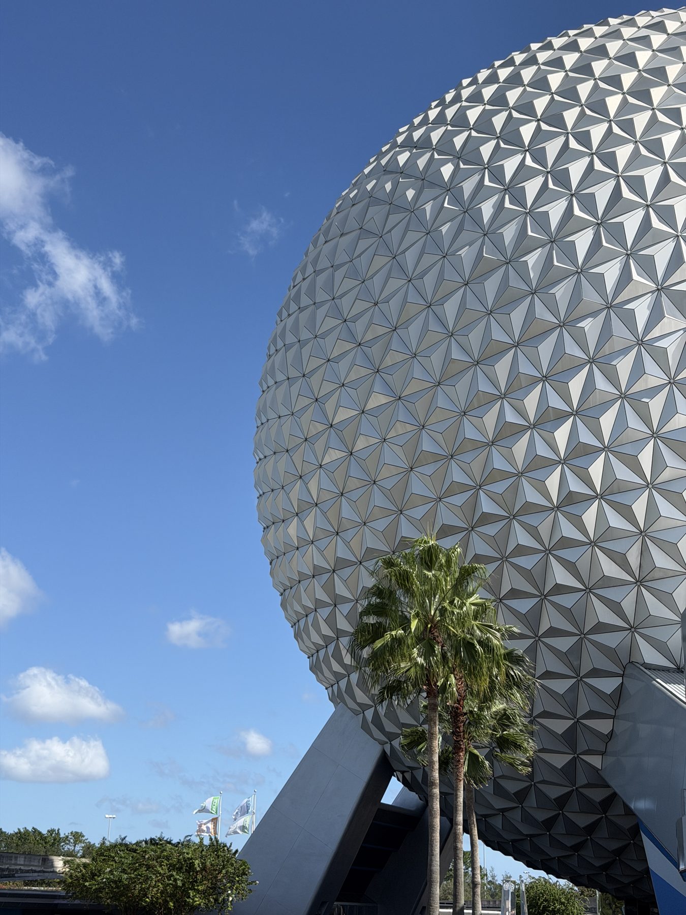 Spaceship Earth at Epcot against a blue sky, with palm trees at its base.