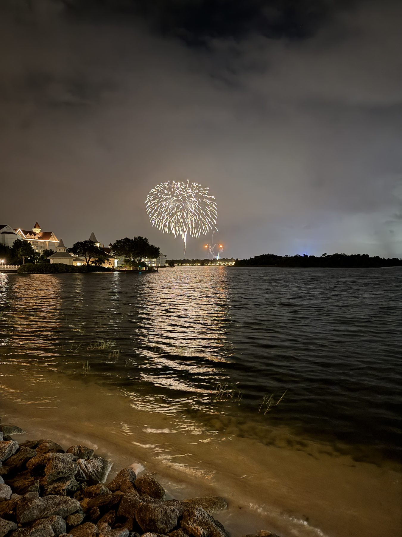 Fireworks over the Seven Seas Lagoon at night, seen from the beach at Disney's Polynesian Village Resort.