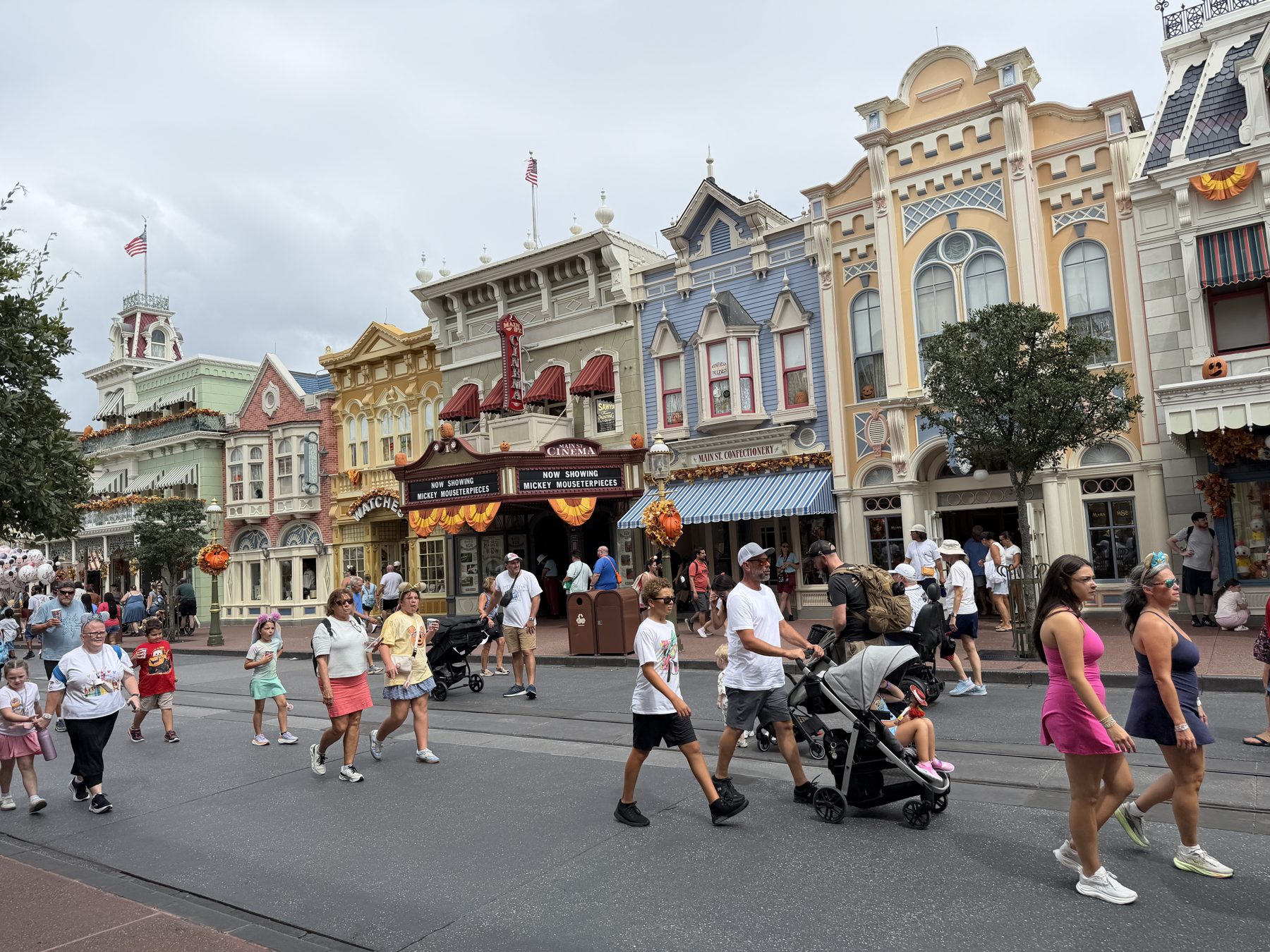 Families walking down Main Street, U.S.A. at Magic Kingdom, with strollers among the crowd.