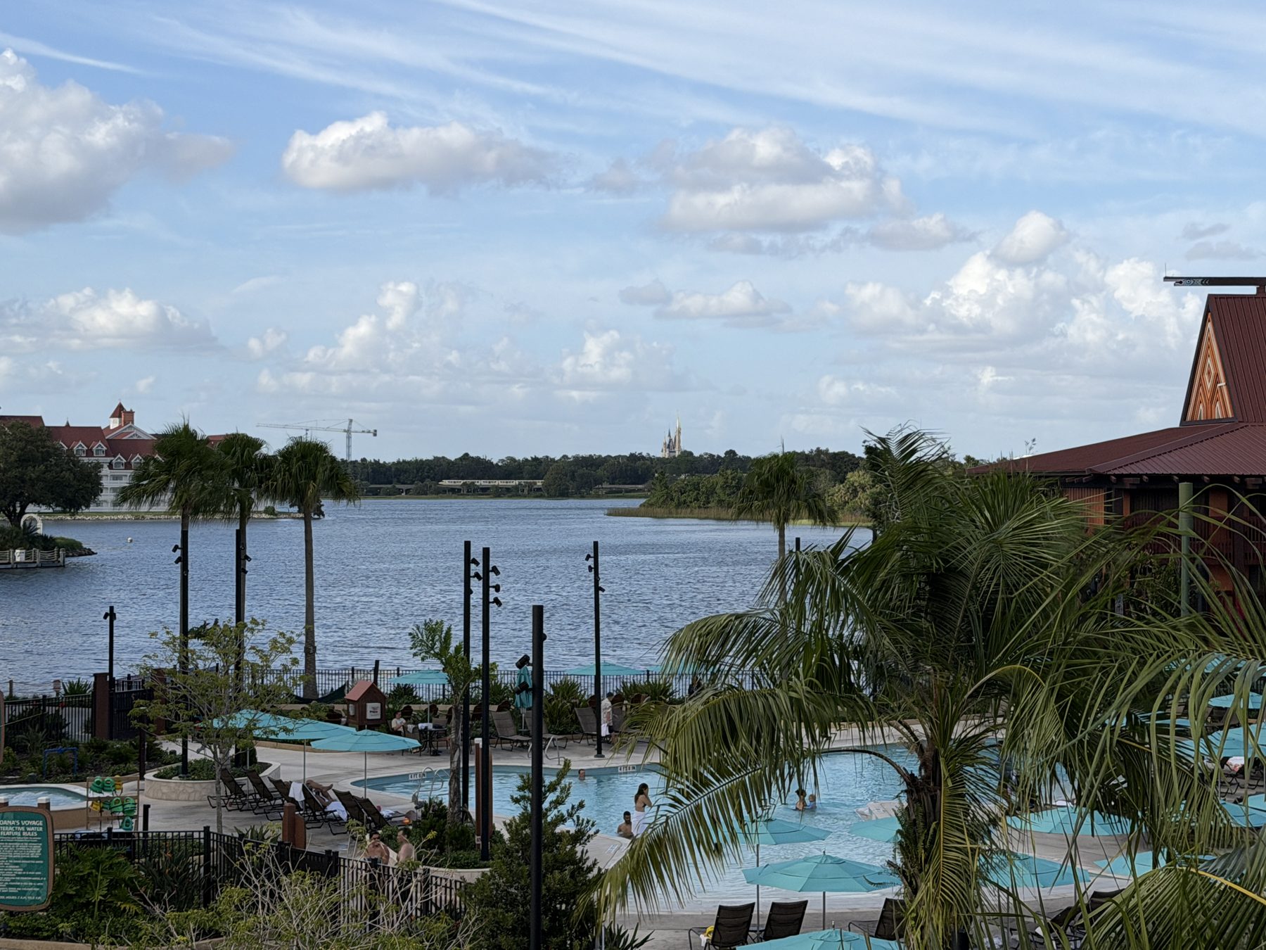 View from a room at Disney's Polynesian Village Resort over the pool, palm trees and the Seven Seas Lagoon.