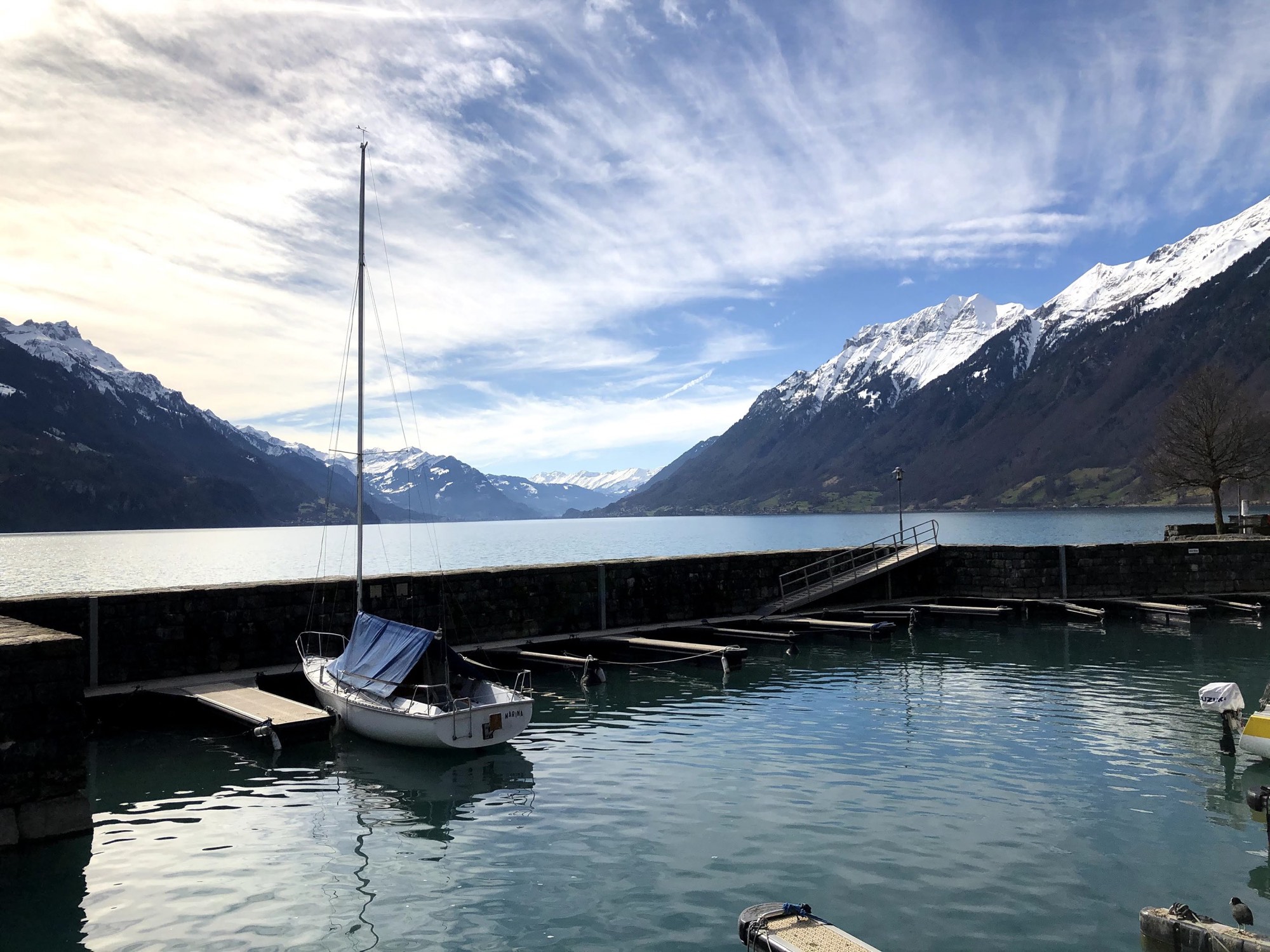 A sailboat moored on an alpine lake beneath snow-capped peaks.