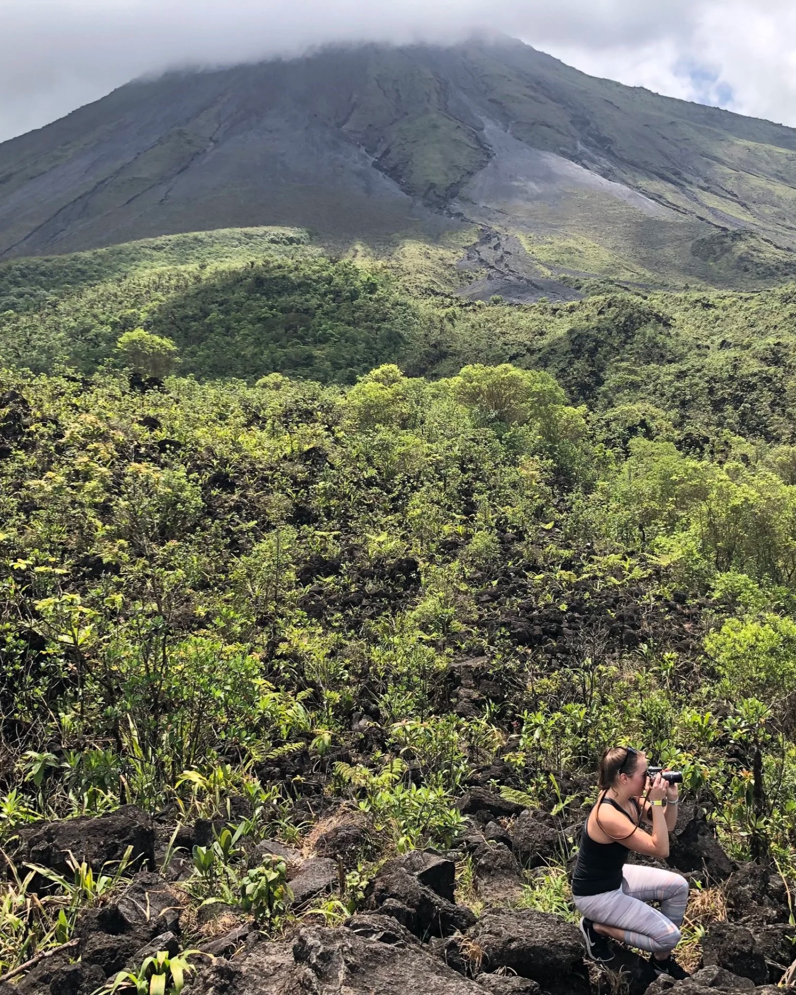 Brittany crouched on a lava field photographing a volcano in Costa Rica.